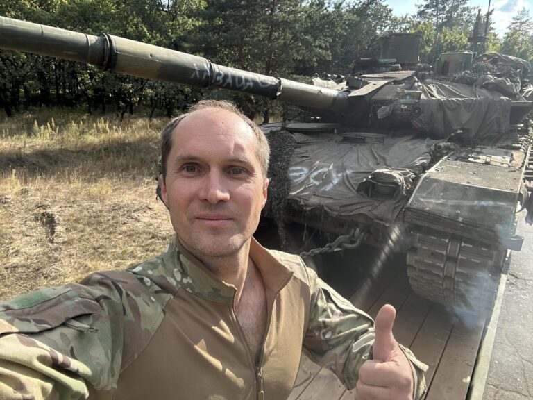 Юрий Бутусов в форме на фоне танка во время службы в армии