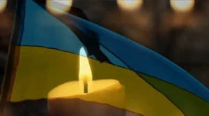 Прапор України з чорною стрічкою та свічка в день жалоби в Одесі