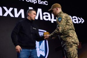 Драпатий у формі тисне руку Федорову на тлі логотипів Бригади
