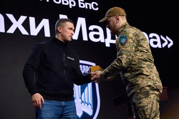 Драпатий у формі тисне руку Федорову на тлі логотипів Бригади