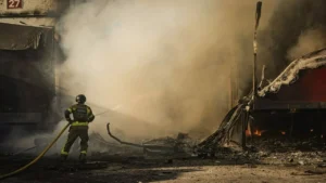 Рятувальник гасить пожежу на складі підприємства в Харкові після удару дрона РФ