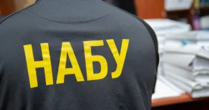 Співробітник НАБУ на тлі документів у справі про збагачення заступника ДПСУ