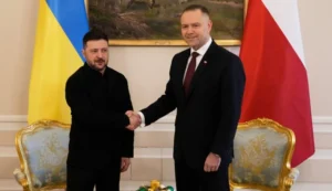 Зеленський і Навроцький тиснуть руки на тлі прапорів України та Польщі