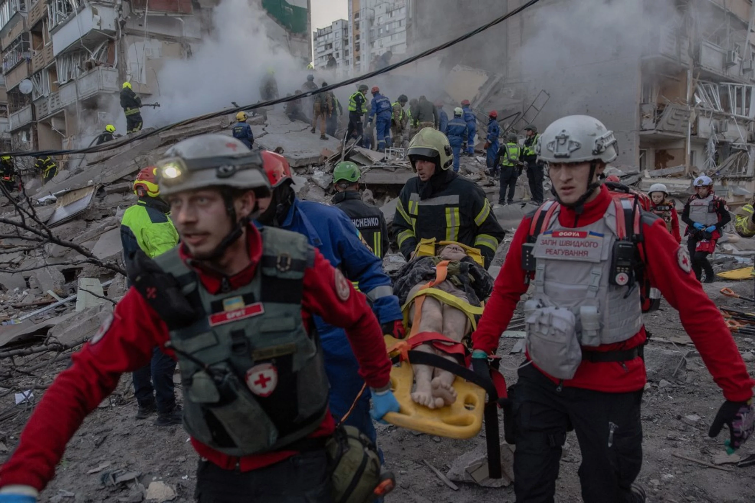 Рятувальники ДСНС несуть пораненого на ношах з-під завалів після ракетного удару