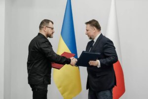 Андрій Сибіга тисне руку польському партнеру на тлі прапорів України та Польщі