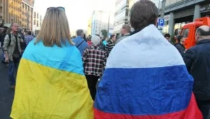 Люди з прапорами України та Росії стоять у натовпі на вулиці