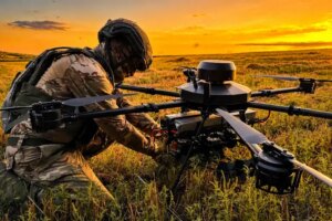 Український військовий налаштовує бойовий дрон на заході сонця