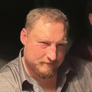 Чоловік середнього віку з короткою сивою бородою в сірій сорочці